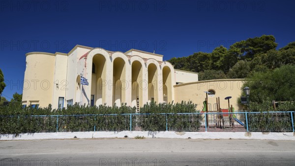 Primary school, Mediterranean building with arches and playground in front of vegetation, Historicism, Art Deco, Rationalism, Portolago, Lakki, Leros, Dodecanese, Greek Islands, Greece