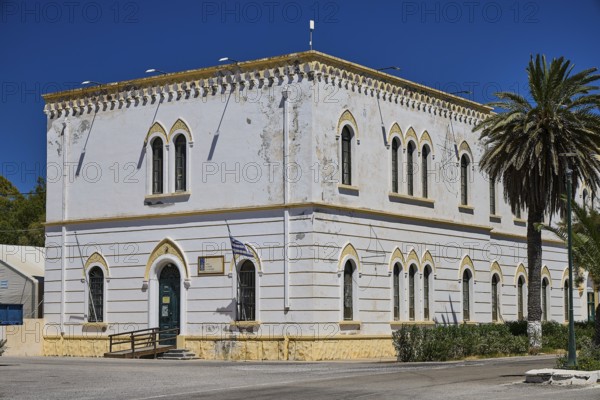 Marine Administration, Caserma Marina 1930, Today Municipal Administration, Classic white building with arched windows, palm trees and Greek flag, Historicism, Art Deco, Rationalism, Portolago, Lakki, Leros, Dodecanese, Greek Islands, Greece
