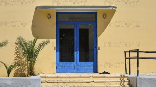 Gymnasium, A blue entrance to a yellow building with plants on the side, Historicism, Art Deco, Rationalism, Portolago, Lakki, Leros, Dodecanese, Greek Islands, Greece