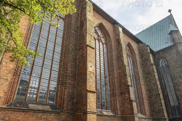 Gothic brick church with large stained glass windows and green trees in the foreground, Cathedral, Verden an der Aller, Lower Saxony, Germany
