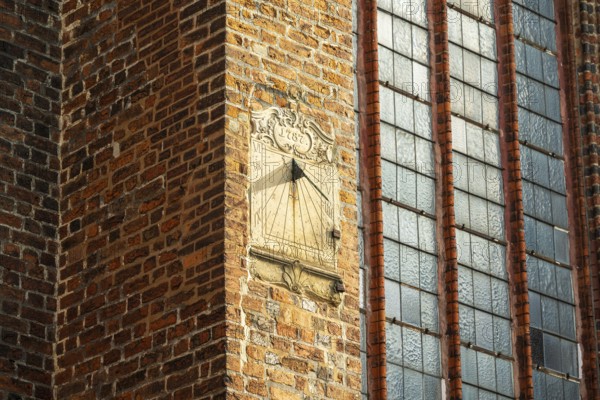 Sundial on a red brick wall next to large Gothic windows, cathedral, Verden an der Aller, Lower Saxony, Germany