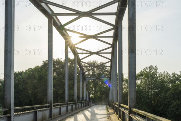 Metal bridge with sunlight, surrounded by trees, shows modern style, Weser cycle path, district of Nienburg Weser, Balge, Lower Saxony, Germany