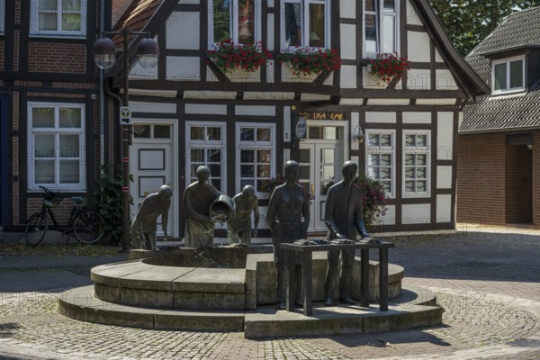Sculptures at a fountain in front of a traditional half-timbered house in a quiet city street, Weser cycle path, Nienburg Weser district, Nienburg Weser, Lower Saxony, Germany
