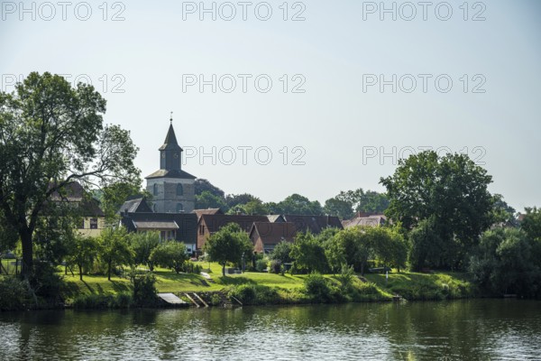 Village by the river with church and lush greenery, relaxed rural atmosphere under a clear sky, Weser, St Martin's Church, Hoya, Lower Saxony