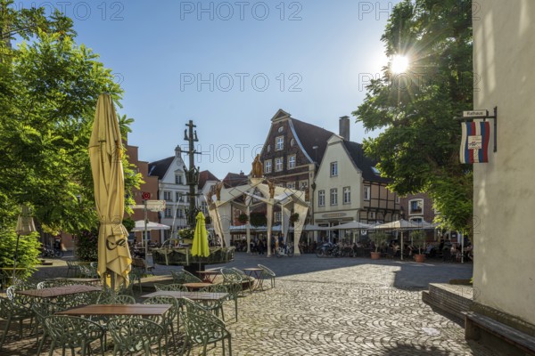 Charming square with half-timbered houses and parasols under a bright blue sky, Warendorf, Münsterland, North Rhine-Westphalia