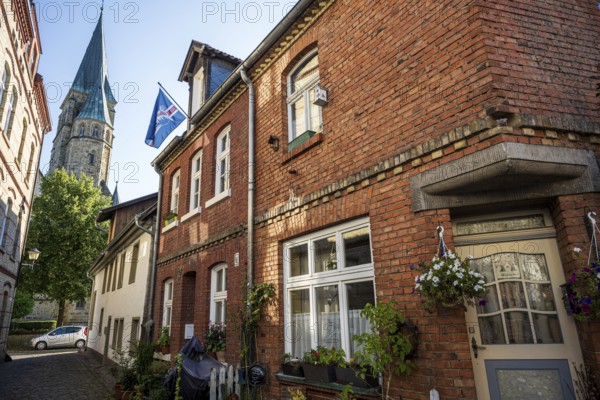 Brick houses with church in the background, surroundings full of plants and flags, Warendorf, Münsterland, North Rhine-Westphalia