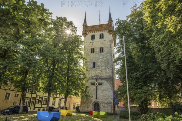 Tower in the town park with colourful chairs and flag, surrounded by tall trees, tower of the old Marienkirche, Marienkirchplatz in Warendorf, Münsterland, North Rhine-Westphalia