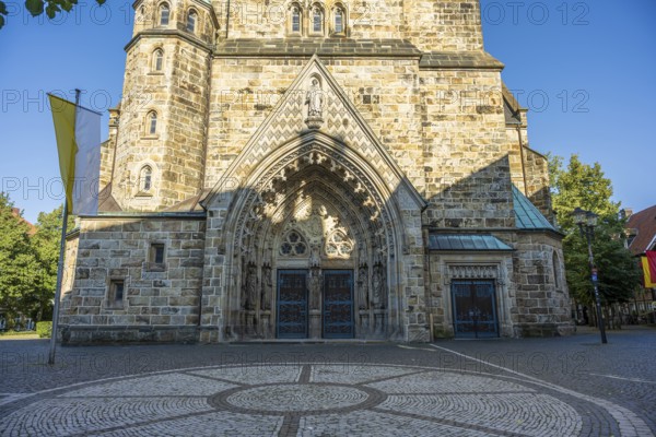 Entrance to a church with richly decorated arch, brick façade and paved forecourt, St Laurentius Church in Warendorf, Münsterland, North Rhine-Westphalia