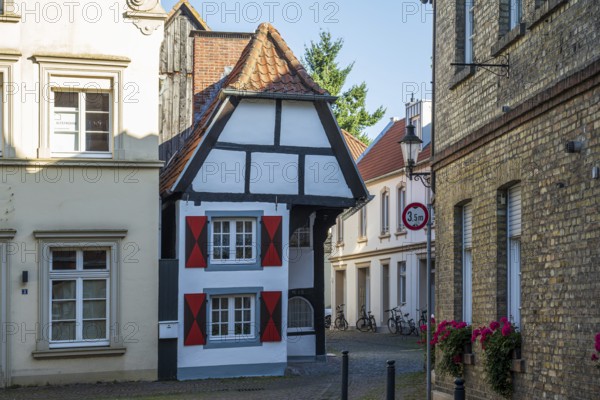 Small half-timbered house in a narrow lane, decorated with eye-catching red shutters, Warendorf, Münsterland, North Rhine-Westphalia