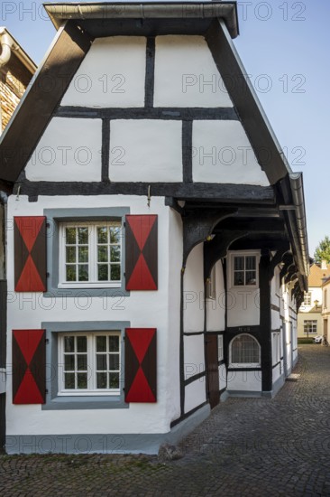 Detailed view of a half-timbered house with striking, colourful shutters on cobblestones, Warendorf, Münsterland, North Rhine-Westphalia