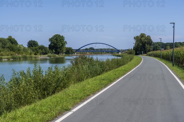Cycle path along a river with a view of a bridge and green landscape, Dortmund-Ems Canal near Lüdinghausen, Münsterland, North Rhine-Westphalia