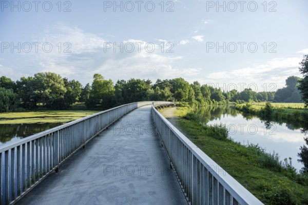Bridge along a quiet river, green surroundings and blue sky reflected in the water, Emssee near Warendorf, Münsterland