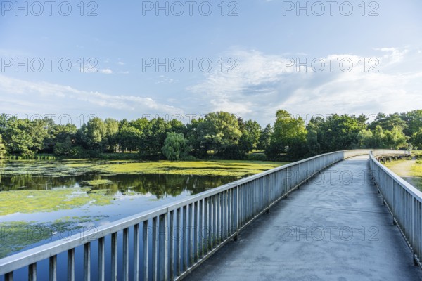 Bridge over a quiet river, surrounded by green trees and blue sky with clouds, Emssee near Warendorf, Münsterland