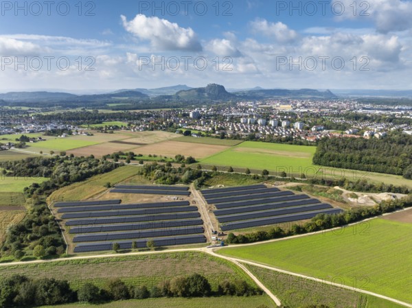 Aerial view, solar modules, solar park, photovoltaics, power generation from solar energy, behind it the town of Singen am Hohentwiel, on the horizon the Hegau Mountains, district of Constance, Baden-Württemberg, Germany