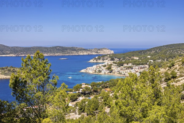 Seascape view at a coastal village on the Mediterranean Sea with a rocky coastline and lush green trees a sunny summer day, Sant Elm, Mallorca, Spain