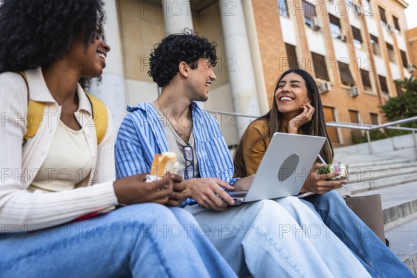 Group of diverse university students sharing a happy moment, laughing and eating lunch together on campus stairs, symbolizing friendship and student life