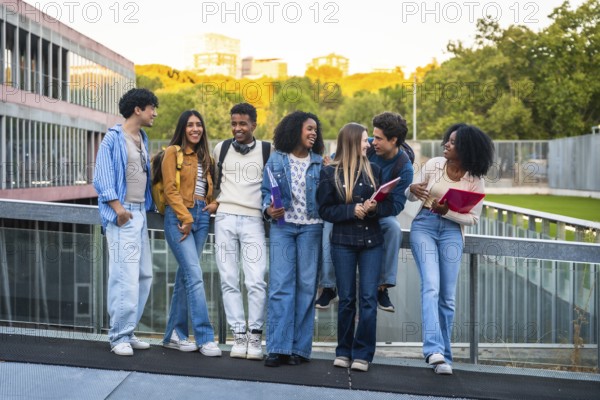 Group of young multicultural students standing together, chatting, and smiling happily after classes on a modern university campus, showcasing friendship and studying