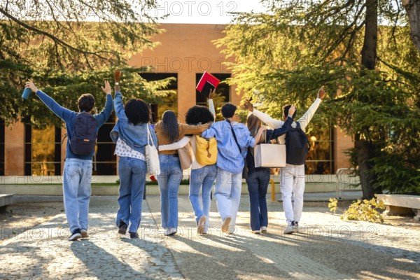Group of diverse university students walking together on campus, embracing friendship and education, raising arms in success and celebration of their college journey
