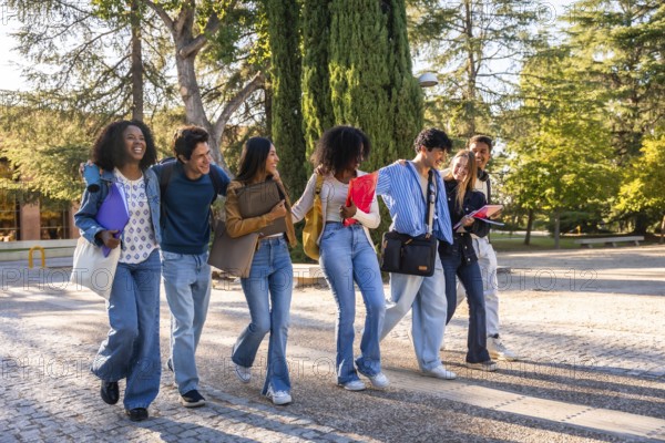Group of young diverse students walking arm in arm, smiling and chatting while carrying books and bags on university campus, embodying friendship, diversity, and education outdoors