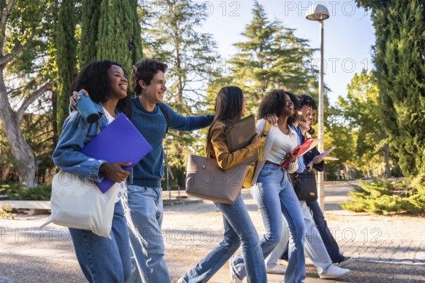 Group of happy university students from different ethnicities walking together on a university campus with books and backpacks, enjoying friendship and education