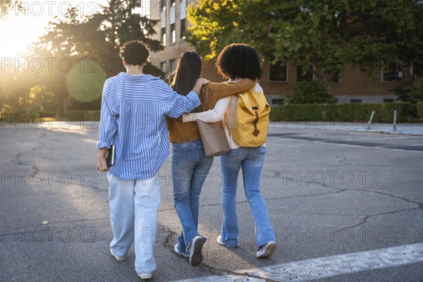Diverse group of female students with arms around each other walking on a university campus at sunset, representing friendship, community, and education