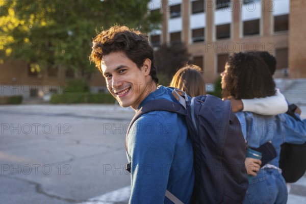 University student smiling at the camera with a backpack, walking with friends on campus, showing happiness and connection during the college experience