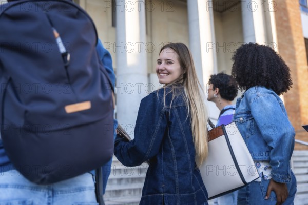 Students walking on campus, young woman smiling and looking back as friends chat and head to class, conveying friendship, diversity, college life and optimism for the semester