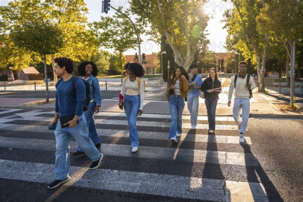 Group of multi ethnic university students walking together across a crosswalk on a sunny day, carrying books and backpacks, representing education, friendship, and diversity