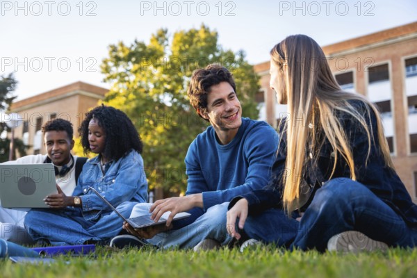 Group of diverse university students collaborating, studying, and engaging in conversations on the grass outdoors, using laptops and enjoying a break on campus