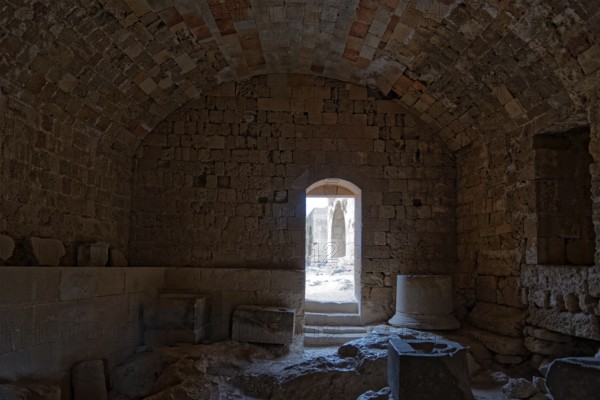 Dark room in ancient stone ruin with vault and doorway leading into the light, Acropolis, Lindos, Rhodes, Island, Greece