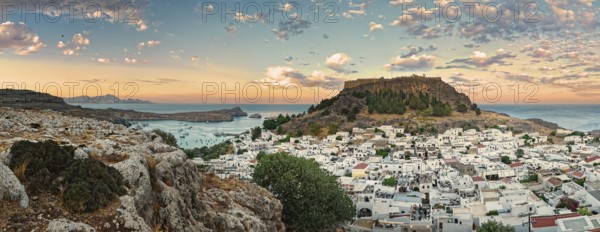 Panoramic view of the Greek town of Lindos by the sea with Acropolis at sunset with dramatic sky and clouds, Acropolis, Lindos, Rhodes, Island, Greece