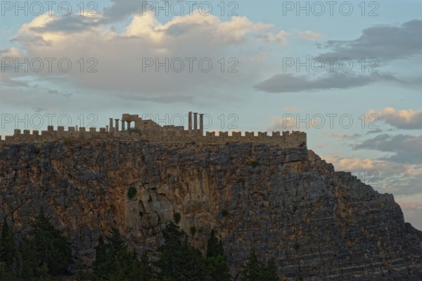 The ancient Acropolis of Lindos on jagged rocks against a dramatic sky at dusk, Acropolis, Lindos, Rhodes, Island, Greece