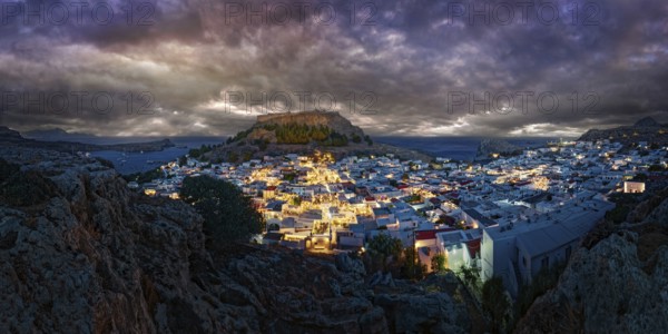 City view of Lindos with the ancient Acropolis at night with dramatic clouds, illuminated buildings and castle, Acropolis, Lindos, Rhodes, Island, Greece