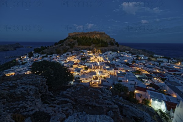 Picturesque Lindos with the ancient Acropolis at dusk with glowing houses and castle in the background, Acropolis, Lindos, Rhodes, Island, Greece