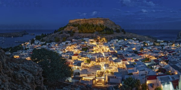 Illuminated town of Lindos with the ancient acropolis and sea in the background, surrounded by rocks, Acropolis, Lindos, Rhodes, Island, Greece