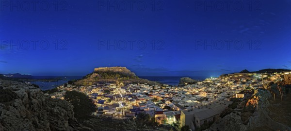 Wide angle photo of the city of Lindos with the ancient Acropolis in a clear night sky with glowing houses, Acropolis, Lindos, Rhodes, Island, Greece