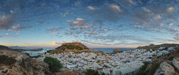 Picturesque Lindos with the ancient Acropolis in the evening light, surrounded by rocks and sea with a dramatic cloudy sky, Acropolis, Lindos, Rhodes, Island, Greece