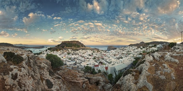 Panoramic view of the Greek town of Lindos by the sea with Acropolis at sunset with dramatic sky and clouds, Acropolis, Lindos, Rhodes, Island, Greece