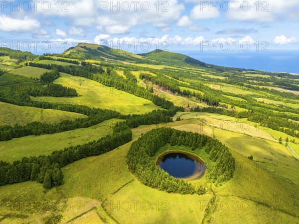Lake Pau Pique and Lush Green Hills with Pastureland and Trees. Shadows of Clouds. Atlantic Ocean. Azores, Sao Miguel Island. Portugal. Aerial Drone Shot