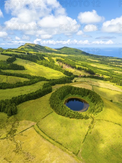 Pond Pau Pique and Lush Green Hills with Pastureland and Trees. Shadows of Clouds. Atlantic Ocean. Azores, Sao Miguel Island. Portugal. Aerial Drone Shot