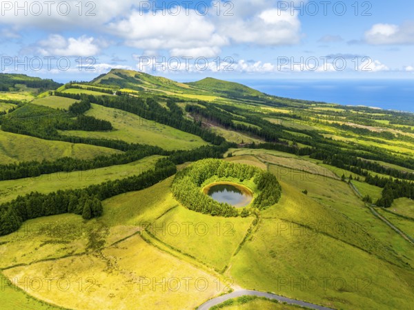Pond Pau Pique and Lush Green Hills with Pastureland and Trees. Shadows of Clouds. Atlantic Ocean. Azores, Sao Miguel Island. Portugal. Aerial Drone Shot