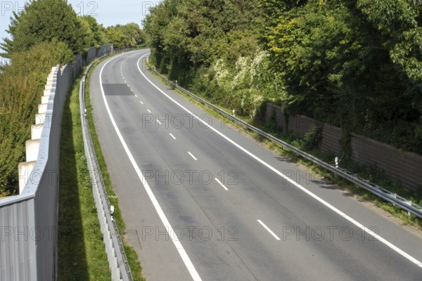 Curved empty road surrounded by lush greenery and sound barriers in borken, germany