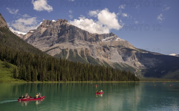 Canoes on Emerald Lake surrounded by forest and the Canadian Rocky Mountains under a clear sky within Yoho National Park in Alberta, Canada, North Canada