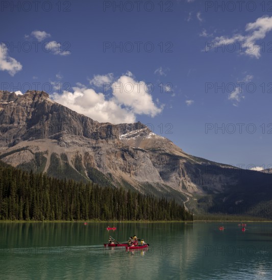 Canoeists on Emerald Lake with the Canadian Rocky Mountains and clouds reflected in the calm water within Yoho National Park in Alberta, Canada, North Canada