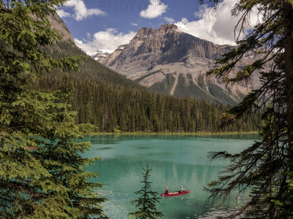 Canoe with explorers on Emerald Lake surrounded by the Canadian Rocky Mountains within Yoho National Park in Alberta, Canada, North Canada