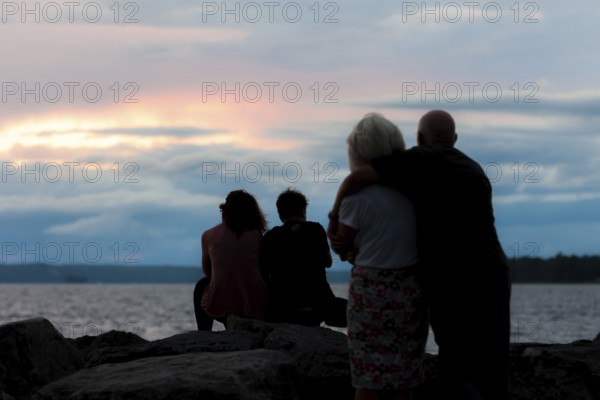 Silhouetted family watching a colorful sunset by the water in Ottawa, Ontario, Canada, North America