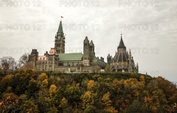The Canadian Parliament building on a hill surrounded by colorful autumn trees, showcasing gothic revival architecture in Ottawa, Ontario, Canada, North America