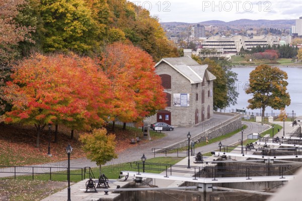 A stone house surrounded by vibrant autumn trees near a river, within a park setting, exuding historical charm in Ottawa, Ontario, Canada, North America