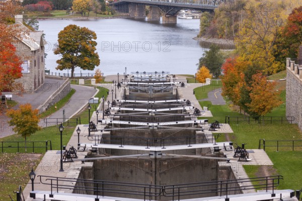 The Rideau Canal with multiple locks surrounded by autumn trees, overlooking a river and bridge in vibrant fall colors leading to the Ottawa River, in Ottawa, Ontario, Canada, North America