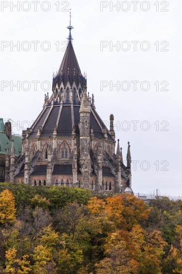 The Canadian Parliament Buildings with spires surrounded by colorful autumn trees in Ottawa, Ontario, Canada, North America